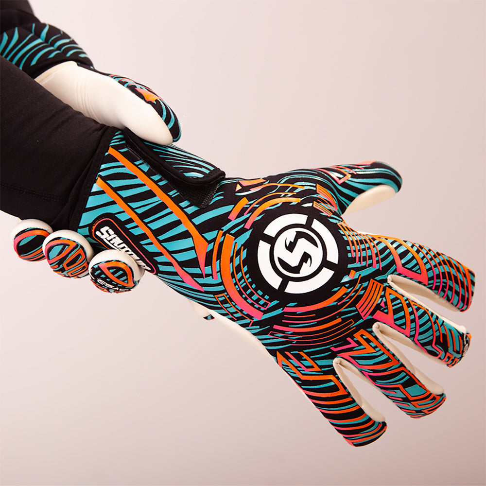 A close-up of a hand wearing a colorful goalkeeper glove with a black, orange, and turquoise pattern, featuring a large circular logo on the back of the hand.