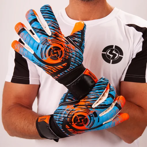 Young goalkeeper diving to save a soccer ball wearing Saviour Classic V1 affordable goalkeeper gloves in vibrant orange and blue.