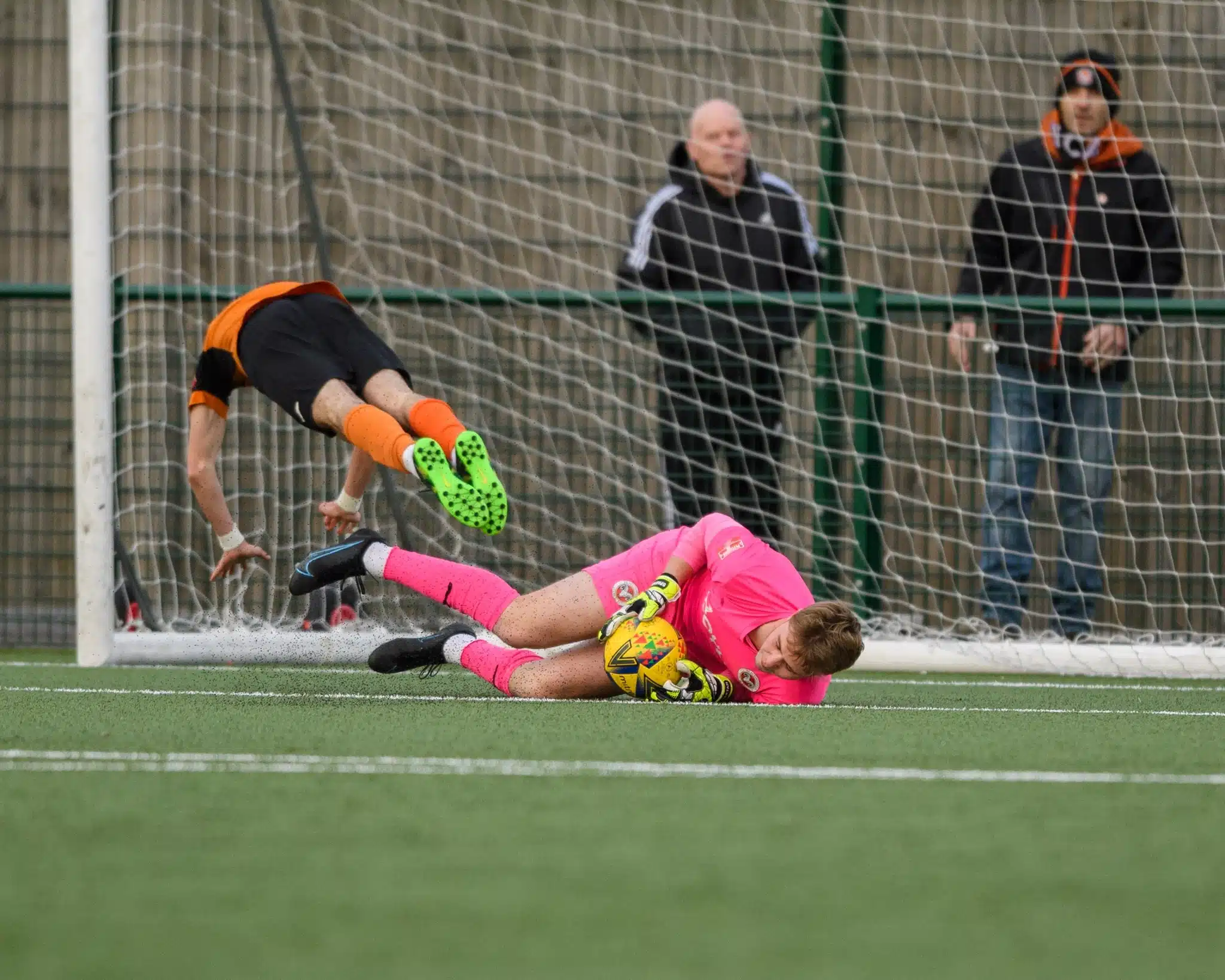 goalkeeper successfully winning a one-on-one challenge on a clear day.