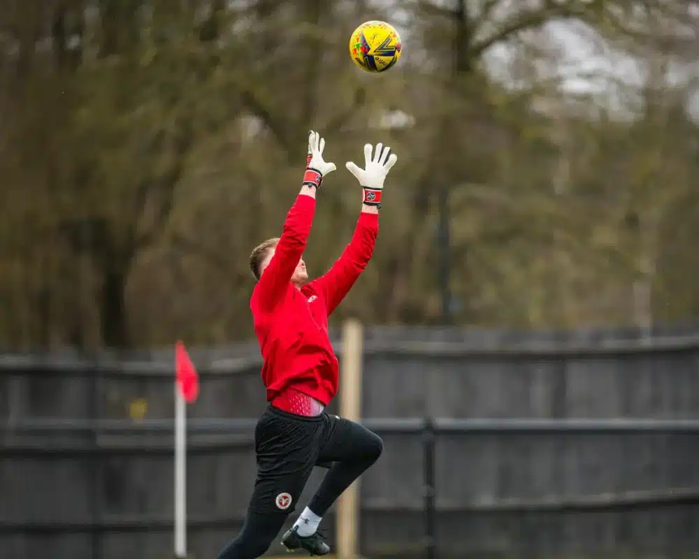 Goalkeeper claiming a cross in windy conditions on a soccer field and learn how goalkeepers deal with windy conditions