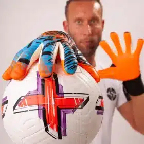 Goalkeeper catching a football with vibrant orange goalkeeper gloves during a match.