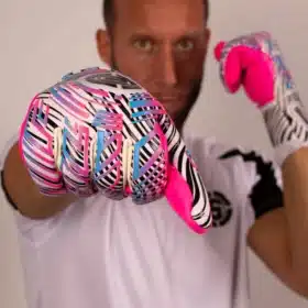 Side view of junior goalkeeper wearing snug pink and blue gloves with finger spines. The pros and cons of removable finger spine goalkeeper gloves