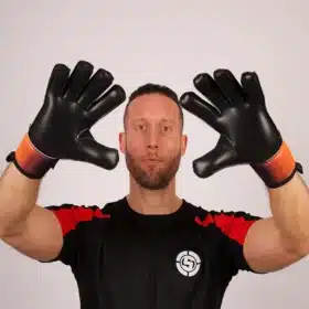 Pair of professional orange and purple goal keeper gloves resting on a soccer ball.