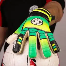 Goalkeeper wearing yellow and green soccer GK gloves parrying a soccer ball.