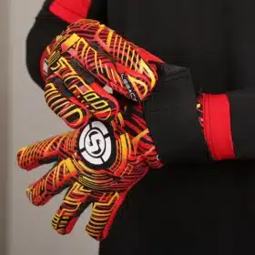 Pair of sleek Strapless Negative Cut Goalkeeper Gloves resting on a soccer pitch.